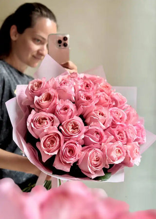 Bouquet of large pink peony roses wrapped in pale pink paper
